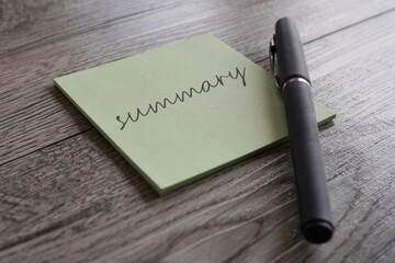 Closeup image notepad with text SUMMARY and pen on table.
