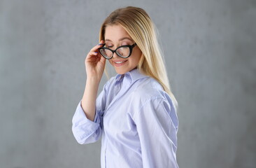 Portrait of a sexy woman in a man's shirt wearing glasses on a gray background looks at the camera....