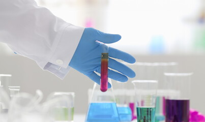 A male chemist holds test tube of glass in his hand overflows a liquid solution of potassium permanganate. Conducts an analysis reaction takes various versions of reagents using chemical manufacturing