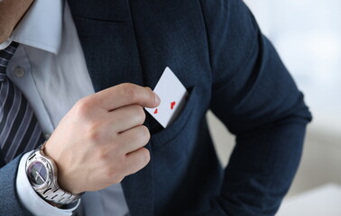 Closeup of mans hand pulling ace card out of suit pocket. Businessman in stylish outfit. Male with...