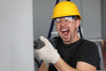 Portrait of person working with tool drilling hole in wall and shouting. Male handyman expressing...