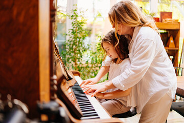Mom and daughter at the piano in the retro interior of a country house.