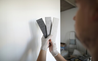 Close-up of samples with various shades and texture for walls. Man holding pieces and selecting...
