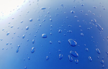 Drops of rainwater on blue metal background after nanoceramics polishing technology closeup