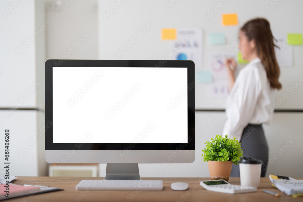 Poster mock up computer on wooden table with businesswoman analysis graph on a whiteboard in background