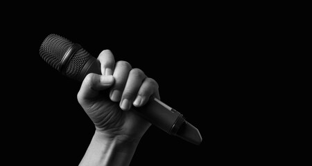 hands holding wireless microphone on black background.
