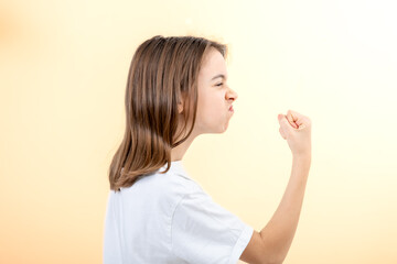 Teenager girl shows fist on yellow background isolated, side view.