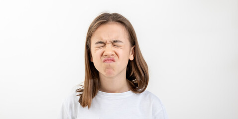 A teenager girl grimaces with displeasure on a white background, isolated.