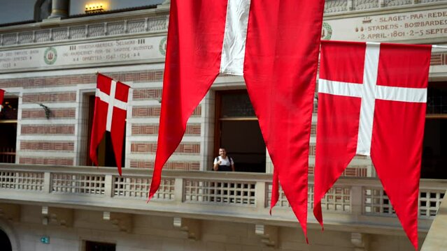 Male tourist poses behind red Danish flags in Copenhagen city hall
