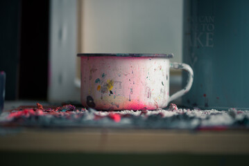 A metal cup covered in remains of acrylic paint