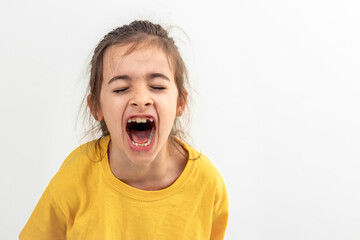 A little Caucasian girl screams loudly, isolated on white background.