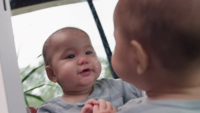 Cute baby seeing their own reflection and kissing themselves in the mirror