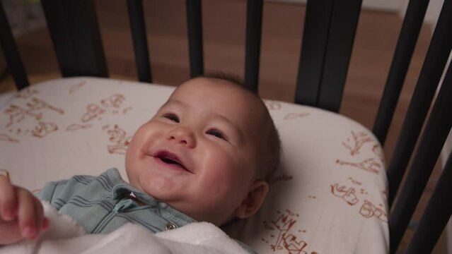 Adorable baby laughing and smiling in crib