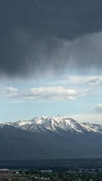 Vertical Time lapse of clouds moving over Utah Valley looking at Loafer Mountain in the distance with snow on the peaks.