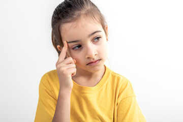 Little girl thinking, holding finger at temple, isolated on white background.