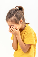 A little girl is crying, covering her face with her hands on a white background.