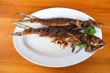 Bandeng Bakar, grilled milkfish with honey and soy sauce. Served with white plate
