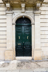 Maltese wooden door with fresh paint and polished brass door furniture.