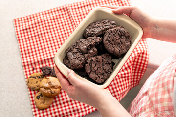 Woman holding tray with chocolate cookies, close up.