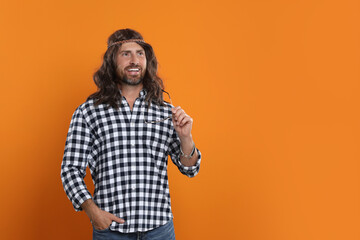 Hippie man with sunglasses on orange background, space for text