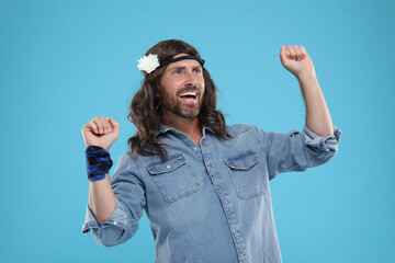 Cheerful hippie man dancing on light blue background