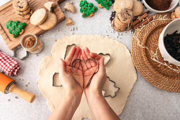 Female hands cut shapes and make Christmas cookies.