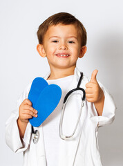 child doctor in white uniform and stethoscope shows thumbs up
