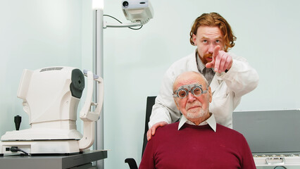 Fototapeta na wymiar Happy elderly man consulting with an ophthalmologist. Medical ophthalmological care. Close-up of a pensioner undergoing a medical examination in a clinic.
