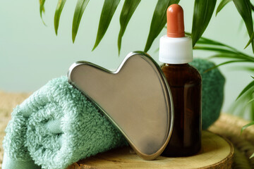 Steel gua sha with towel and oil in amber glass bottle
