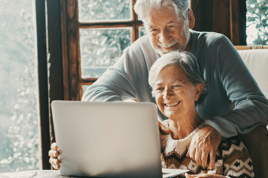 Old senior couple at home use laptop for video call to friends or parents. Distance and remote communication with laptop and internet technology. Elderly people enjoy day and lifestyle using notebook
