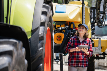 Female farmer with a digital tablet next to agricultural tractor.
