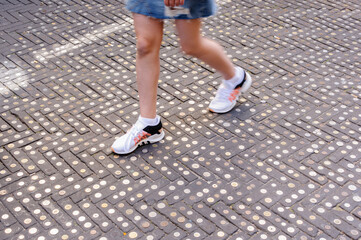 A person walks over a pavement with hundreds of coins glued to it.