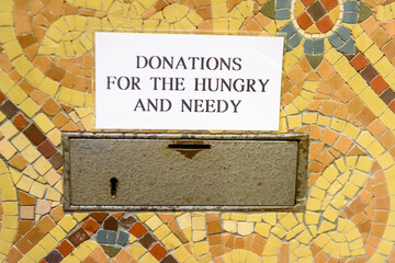 Collection box in a church asking for donations for the hungry and needy.