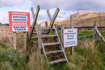 Style over a fence, with warning signs at a railway track, County Donegal, Ireland