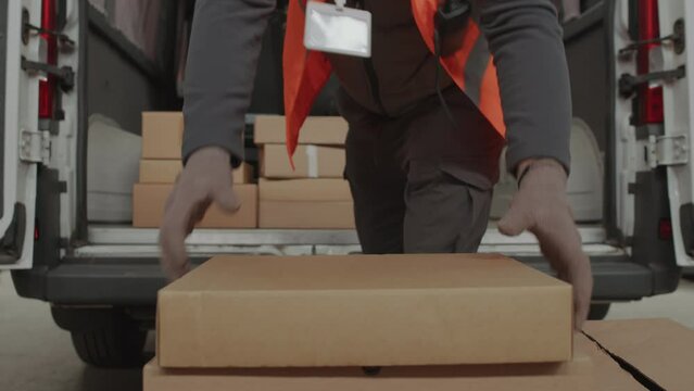 Cropped shot of storeman putting boxes for shipment into cargo van while working at warehouse