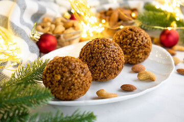 Christmas nut balls cookie on white plate with almond and cashew, Christmas lights bokeh and decor on background. Recipe of dessert for New Year and Christmas holidays menu.