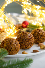 Christmas nut balls cookie on white plate with almond and cashew, Christmas lights bokeh and decor on background. Recipe of dessert for New Year and Christmas holidays menu.