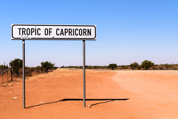 Road sign at the tropic of capricorn  on the road from Windhoek to Rehoboth, Namibia. - obrazy, fototapety, plakaty