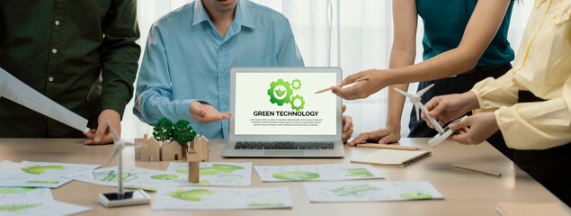 Green technology logo displayed on green business laptop while business team presenting green...