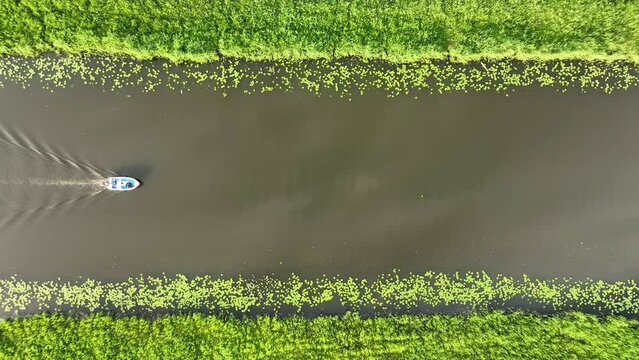 Aerial view of a canal boat in the Netherlands. Boat ride on the canals. View from a drone. Canals with water for agriculture. Fields and meadows. Landscape from a drone.