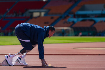 Disabled athletes prepare in starting position ready to run on stadium track - obrazy, fototapety, plakaty