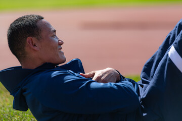 Disabled athletic man stretching and warming up before running on stadium track