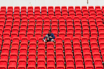 Disabled athletes in a blue shirt sitting on the red seats at the stadium, Prepare for running training.