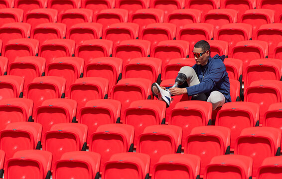 Disabled athletes in a blue shirt sitting on the red seats at the stadium, Prepare for running training. - Powered by Adobe