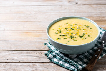 Corn soup in green bowl on wooden table. Copy space