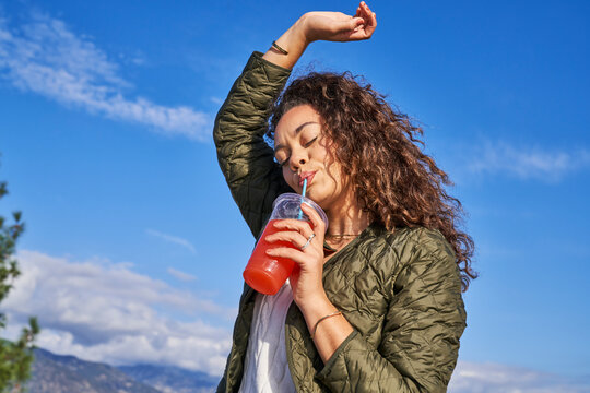woman enjoys pink lemonade outdoors arm over head