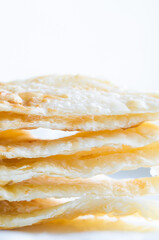 Close up six triangular roti dough stacked on white dish.