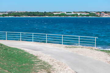 View of the sea from the beach with a footpath and fence on the shore . Medulin coast at Adriatic Sea in Istria Croatia