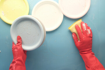 sponge , rubber gloves and colorful plate on blue