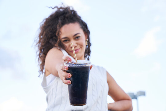 woman enjoying soft drink outdoors holding drink out